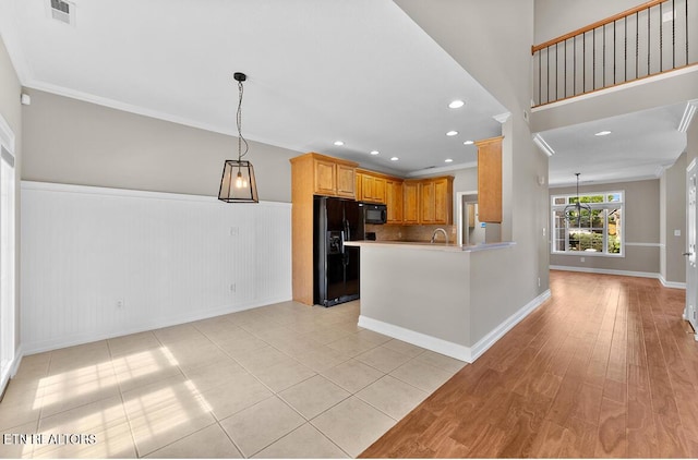 kitchen featuring crown molding, a wainscoted wall, visible vents, pendant lighting, and black appliances