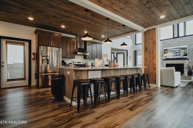 kitchen featuring dark wood-style floors, appliances with stainless steel finishes, wooden ceiling, and a kitchen bar