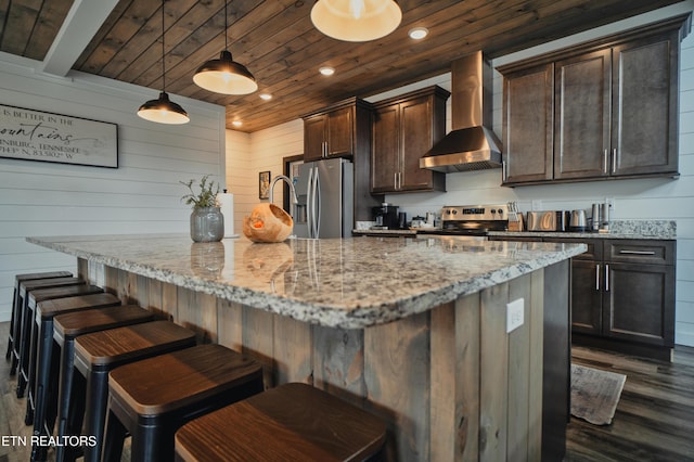 kitchen featuring a kitchen bar, wall chimney exhaust hood, stainless steel appliances, dark wood-type flooring, and wooden ceiling