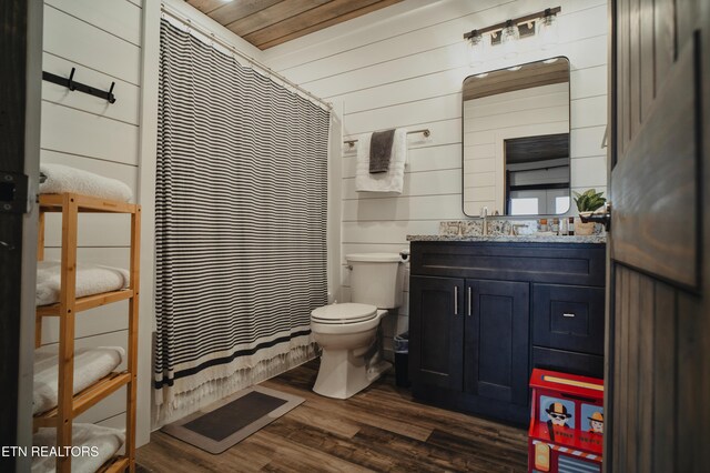 full bath with toilet, a shower with shower curtain, wood walls, vanity, and wood finished floors