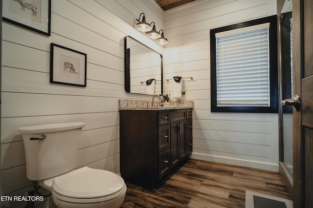 bathroom featuring baseboards, toilet, wood walls, vanity, and wood finished floors