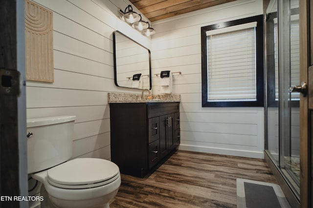 full bath featuring a stall shower, vanity, wood walls, and wood finished floors