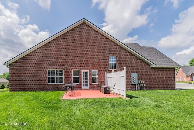 back of property with a yard, a patio, and brick siding