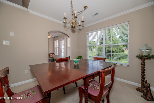 carpeted dining space featuring baseboards, visible vents, a chandelier, crown molding, and arched walkways