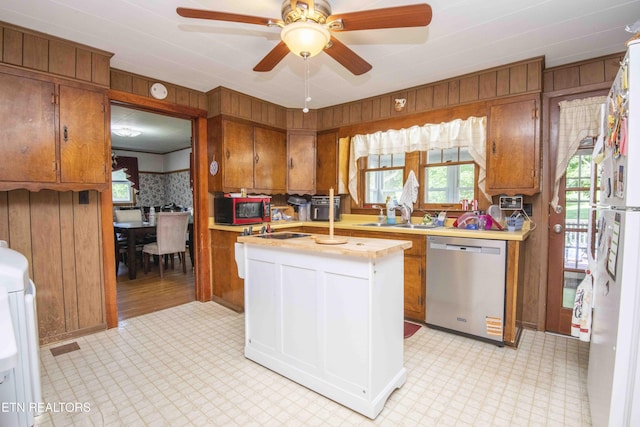 941 Pine Top St, Lenoir City, TN 37772 - kitchen featuring wood walls, light floors, light countertops, brown cabinets, and dishwasher