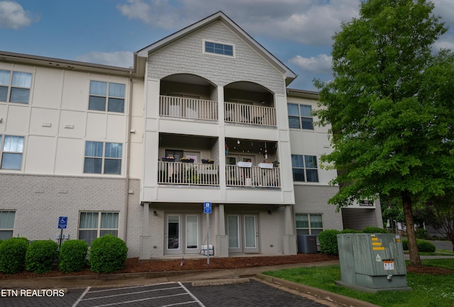view of property featuring central air condition unit and uncovered parking