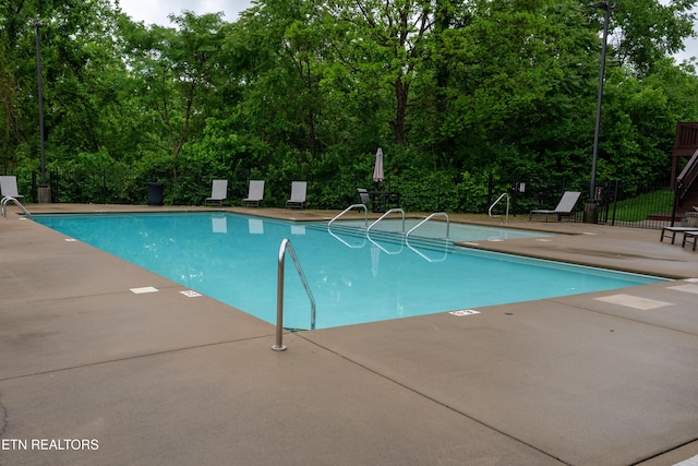 community pool with a patio and fence