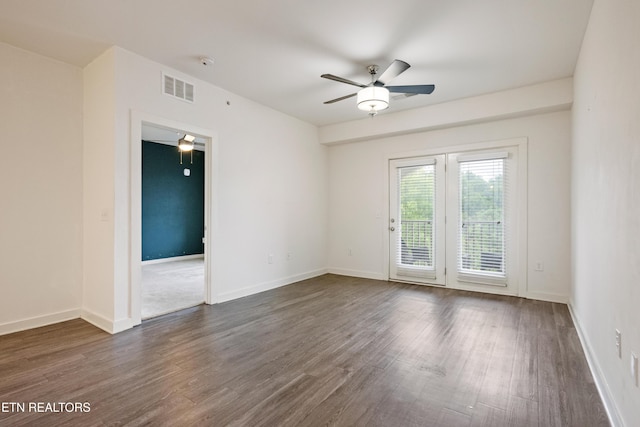 spare room with ceiling fan, baseboards, dark wood-type flooring, and visible vents