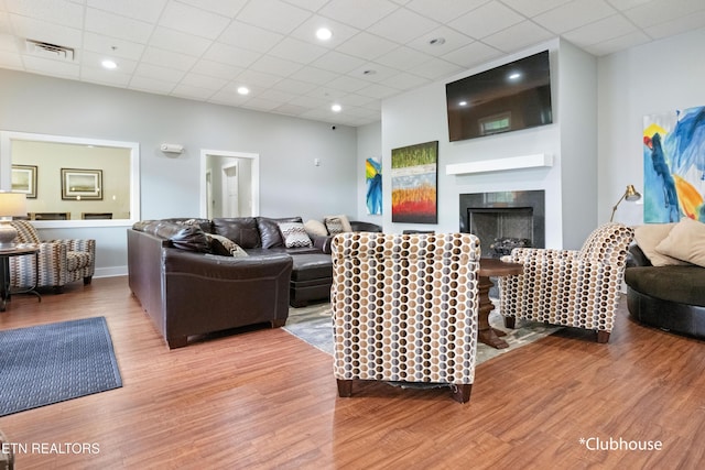 living room featuring a drop ceiling, visible vents, wood finished floors, and a fireplace
