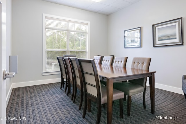 dining room featuring dark colored carpet and baseboards