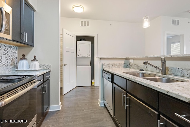 kitchen with stacked washer and clothes dryer, wood finished floors, a sink, visible vents, and appliances with stainless steel finishes