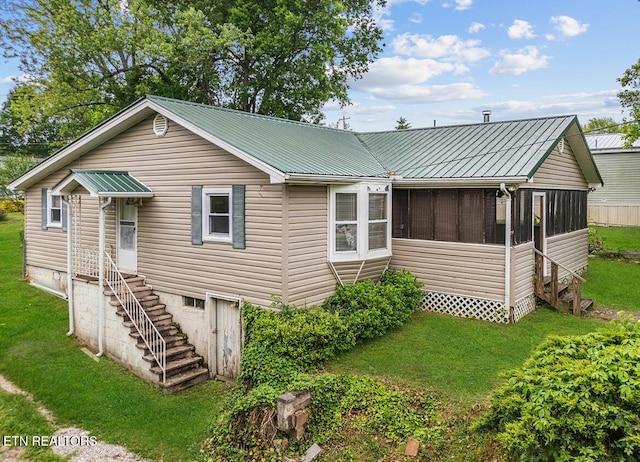 rear view of property with a lawn, a sunroom, and metal roof