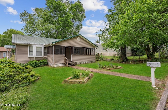 single story home featuring a sunroom, a front yard, and metal roof