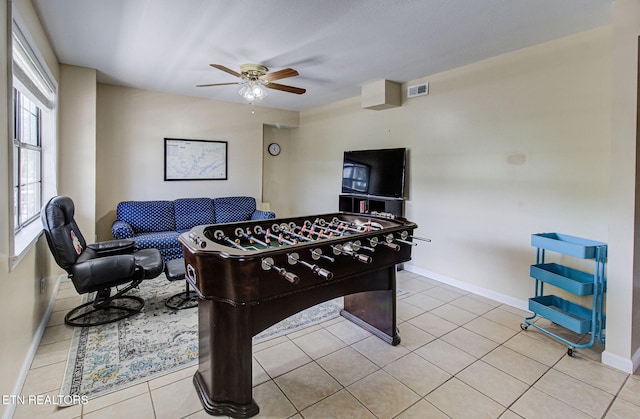 recreation room with a ceiling fan, baseboards, and light tile patterned floors