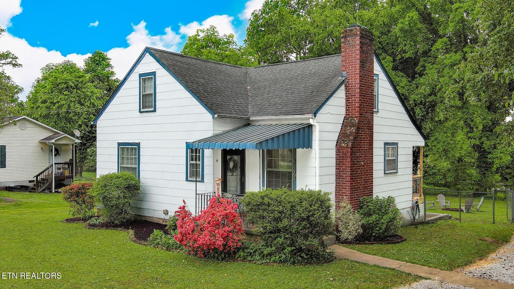 bungalow-style house featuring a front lawn, fence, roof with shingles, and a chimney