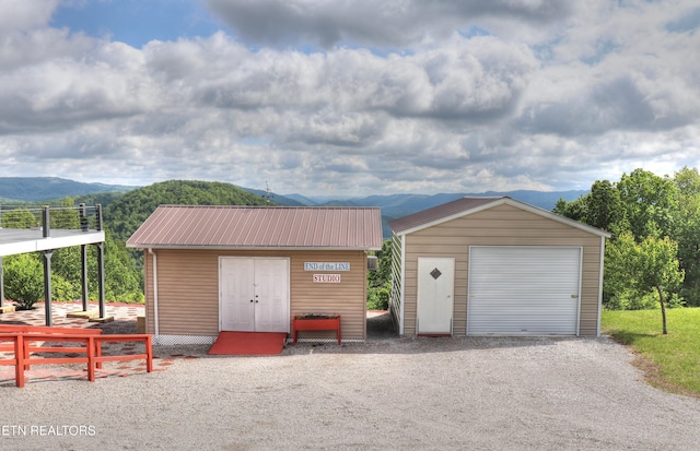 detached garage featuring a mountain view, fence, and driveway
