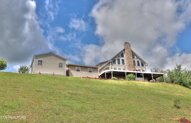 rear view of property featuring a chimney and a yard