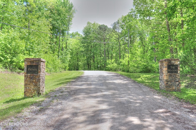 view of dirt / gravel road featuring a forest view