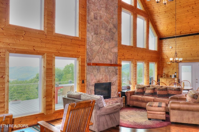 living area featuring high vaulted ceiling, a chandelier, a fireplace, plenty of natural light, and wooden walls