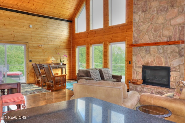 living room with high vaulted ceiling, plenty of natural light, wood finished floors, wood walls, and wooden ceiling