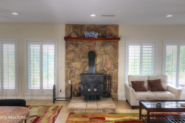 living area with tile patterned floors, baseboards, a wood stove, and recessed lighting