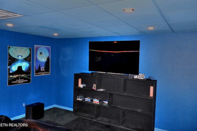 living area featuring a drop ceiling, carpet, and baseboards