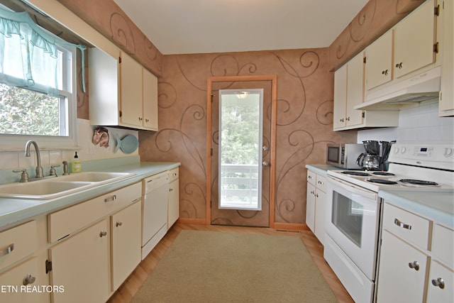 kitchen featuring under cabinet range hood, white appliances, a sink, and a healthy amount of sunlight