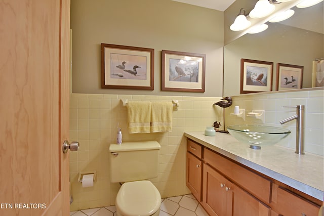 bathroom with tile patterned flooring, tile walls, a wainscoted wall, vanity, and toilet