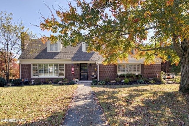 view of front of house with a front lawn, brick siding, and a chimney