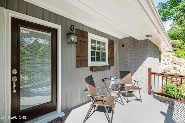 doorway to property with brick siding and covered porch