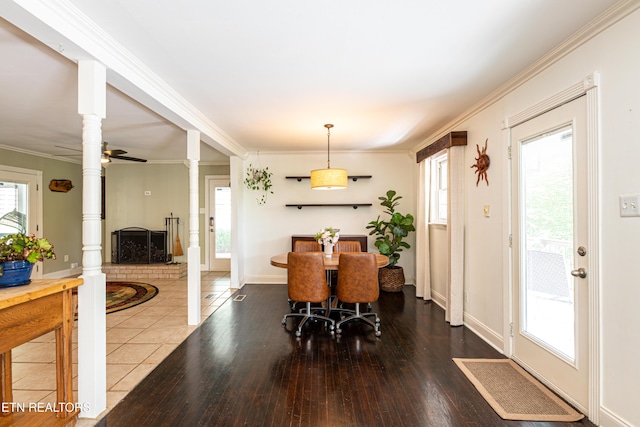 dining space featuring baseboards, hardwood / wood-style floors, crown molding, and decorative columns