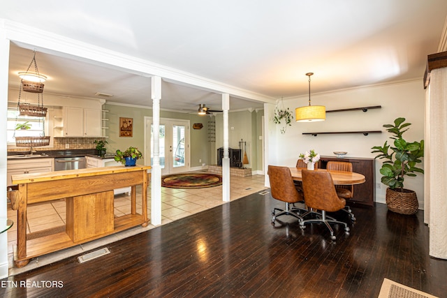 dining space with hardwood / wood-style floors, decorative columns, crown molding, ceiling fan, and baseboards