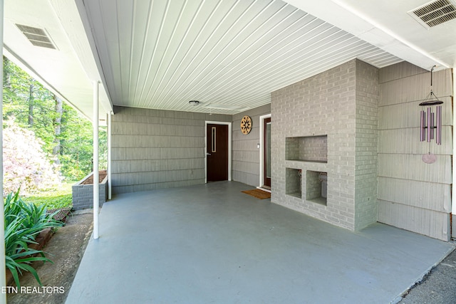 view of patio featuring cooling unit, visible vents, and an attached carport