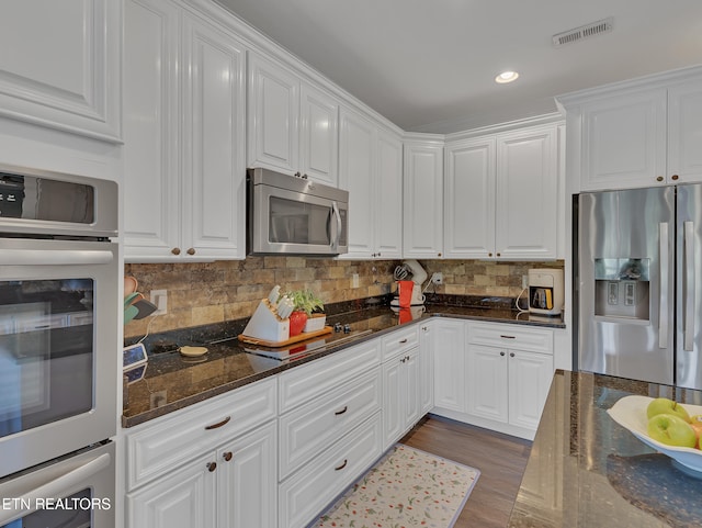 1810 Griffitts Mill Cir, Maryville, TN 37803 - kitchen featuring appliances with stainless steel finishes, white cabinets, tasteful backsplash, wood finished floors, and dark stone counters