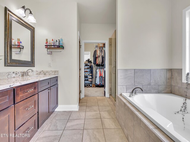 1810 Griffitts Mill Cir, Maryville, TN 37803 - bathroom featuring a walk in closet, vanity, a bath, a stall shower, and baseboards