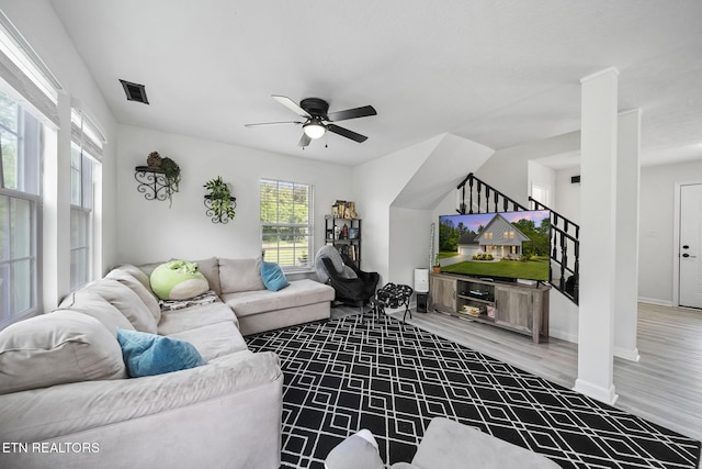 living room featuring wood finished floors, visible vents, baseboards, and ceiling fan