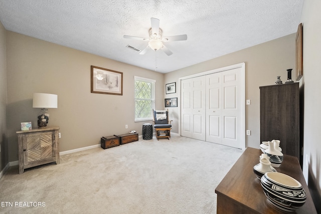 carpeted office space featuring a textured ceiling, baseboards, a ceiling fan, and visible vents