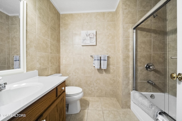 full bath with toilet, tile walls, a textured ceiling, bath / shower combo with glass door, and vanity