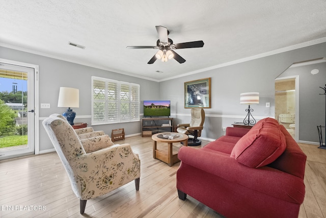 living area featuring a ceiling fan, a wealth of natural light, visible vents, and light wood-type flooring