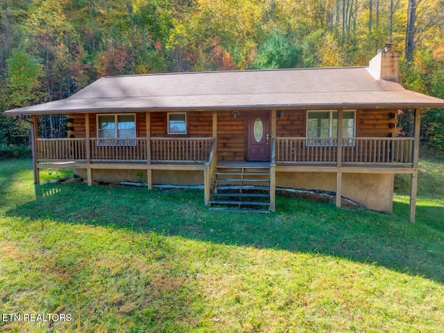 cabin featuring a chimney, a front lawn, covered porch, and log exterior