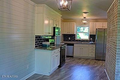 kitchen with a notable chandelier, decorative backsplash, dark countertops, white cabinets, and appliances with stainless steel finishes