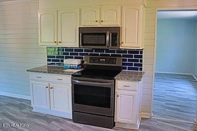 kitchen featuring baseboards, stainless steel appliances, dark stone counters, and decorative backsplash