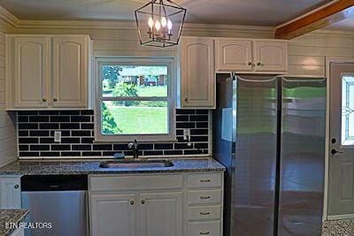 kitchen featuring a sink, white cabinetry, dark stone countertops, decorative backsplash, and stainless steel appliances