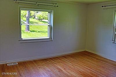 empty room featuring baseboards, visible vents, and wood finished floors