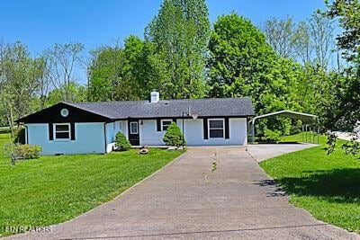 ranch-style home with a front lawn, driveway, and a carport