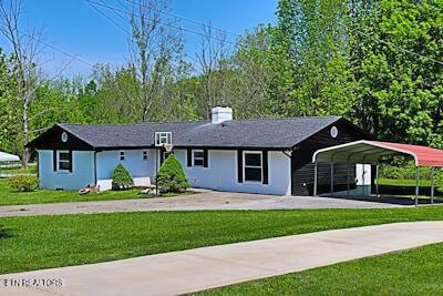 single story home with a detached carport, concrete driveway, and a front yard