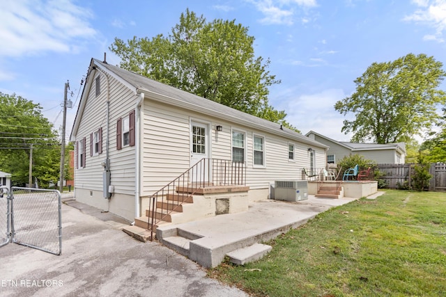 rear view of house with a yard, central AC unit, a patio, and fence