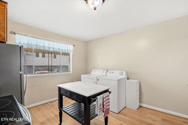 laundry area with washing machine and dryer, light wood-type flooring, and baseboards