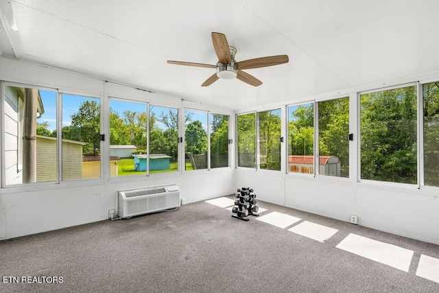 unfurnished sunroom with ceiling fan, a wall mounted air conditioner, and a healthy amount of sunlight