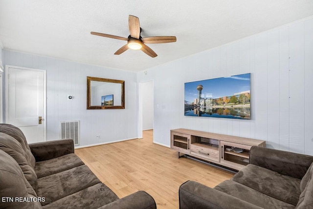 living room featuring visible vents, wood finished floors, baseboards, and ceiling fan